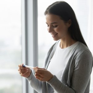 A woman smiling as she sees the results from a pregnancy test