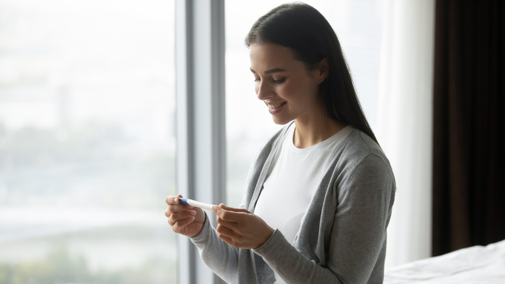 A woman smiling as she sees the results from a pregnancy test