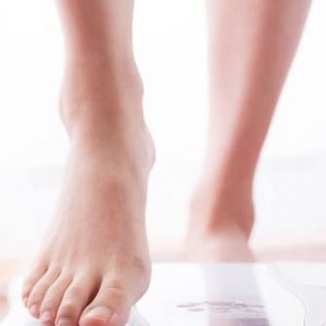 underweight woman stepping on scales
