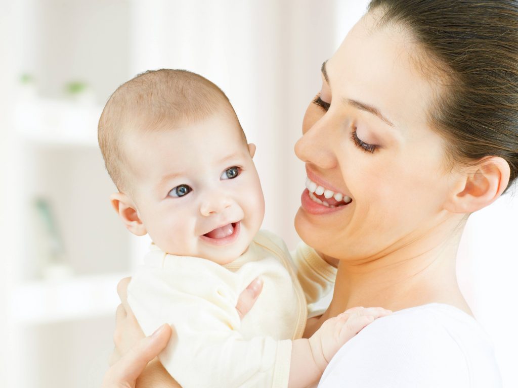 lady holding a baby and smiling