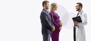 A doctor talking to a couple, with the woman heavily pregnant