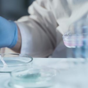 a person in a lab coat using a pipette