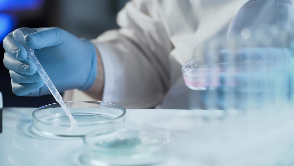 a person in a lab coat using a pipette