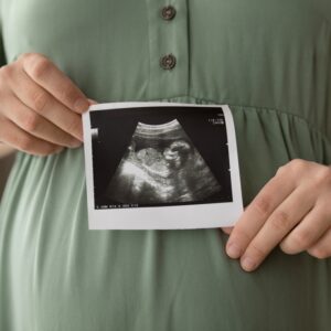 pregnant woman holding a scan photo in front of her belly