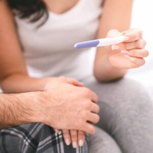 woman showing her partner a pregnancy test