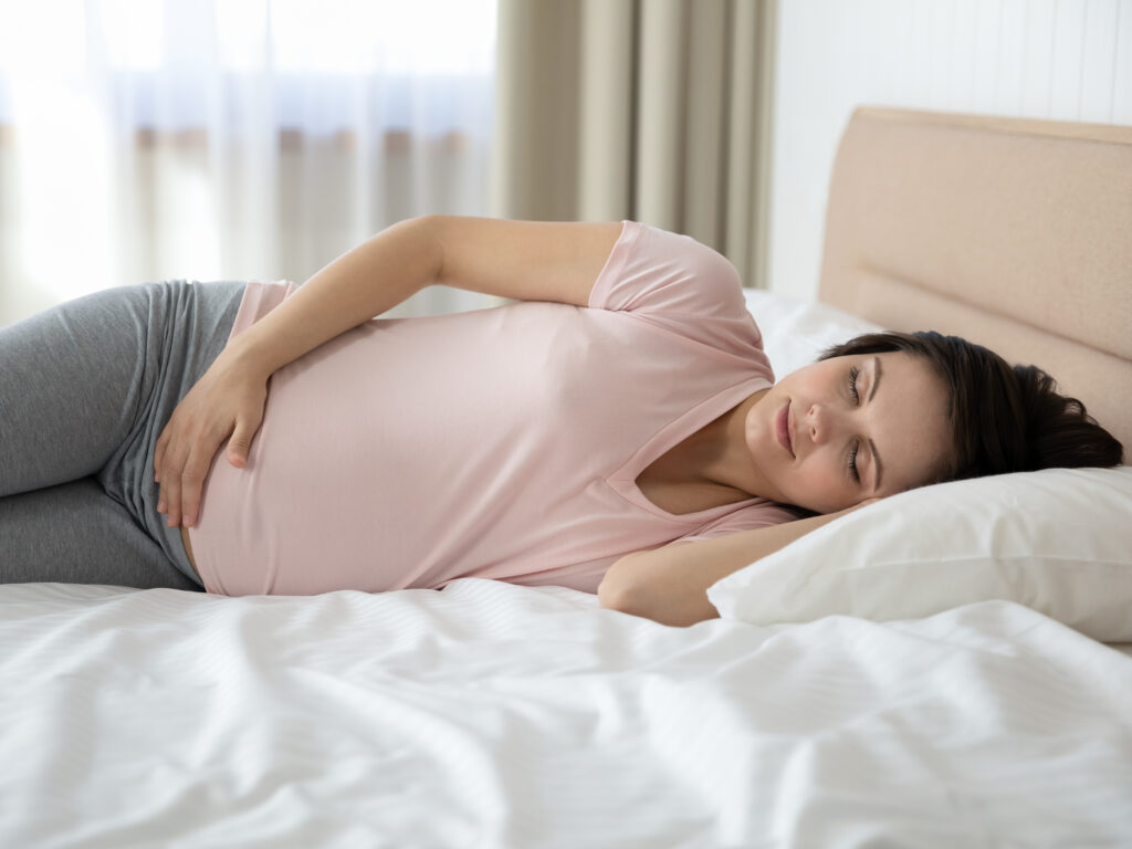 Pregnant woman lying on her side in bed